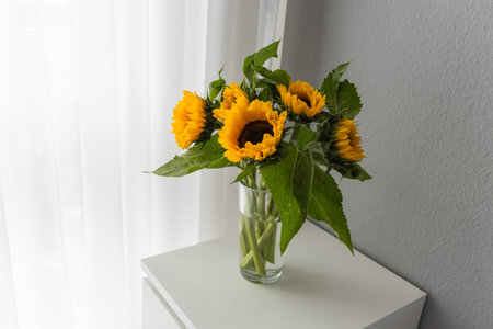 Bouquet of sunflowers in vase on table near windowの写真素材