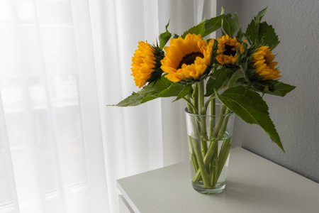 Sunflowers in a glass vase on a white table.の写真素材