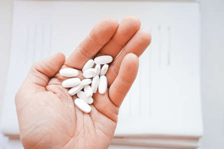 Medicine pills or capsules in hand, palm or fingers of a doctor or nurse.