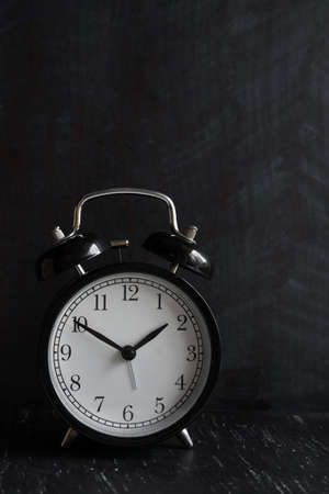 Retro alarm clock on wooden table. Black backgroundの写真素材