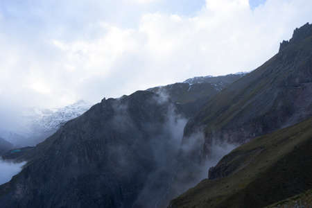 Aerial view of misty mountains at sunrise. Clouds drift amid rocky cliffs.の写真素材