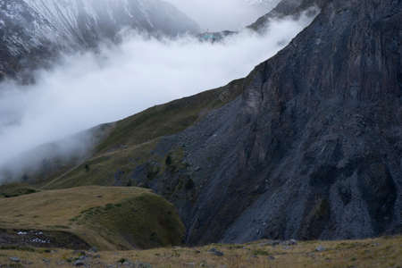 Aerial view of misty mountains at sunrise. Clouds drift amid rocky cliffs.の写真素材