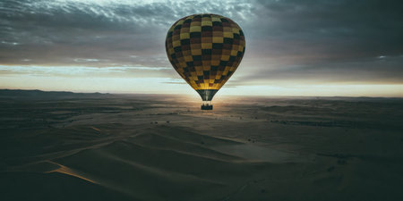 Hot Air Balloon Flying Over Deserted Sand Dunes at Sunriseの素材
