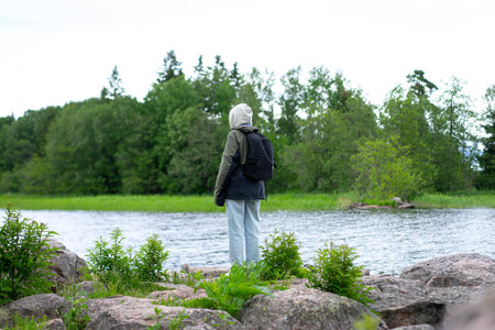girl in warm clothes stands on the shore of a mountain lake.の写真素材