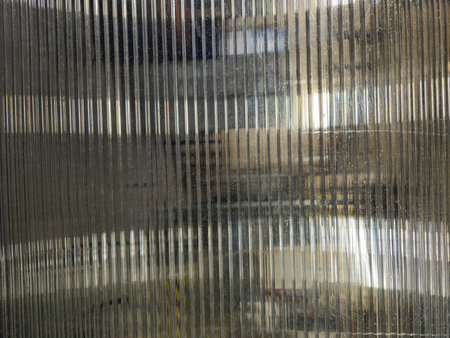 Textured glass panels offering an abstract perspective, capturing reflections and refractions in soft lighting, delivering a modern and artistic visual appeal.の写真素材