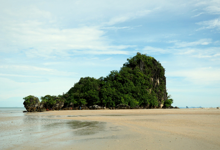 small island in tropical sea green and rock surrounded by sand and waterの写真素材