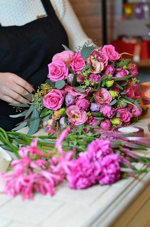Woman florist tying the ribbon on the bouquet of rosesの写真素材