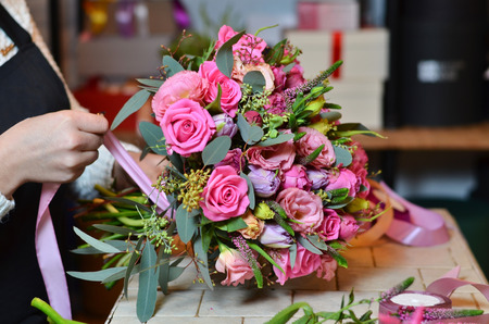 Woman florist tying the ribbon on the bouquet of rosesの写真素材