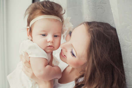 Mother playing with cute baby girl indoorの写真素材