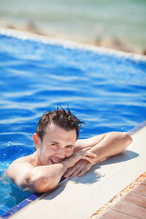 wet tanned young man posing in the swimming pool
