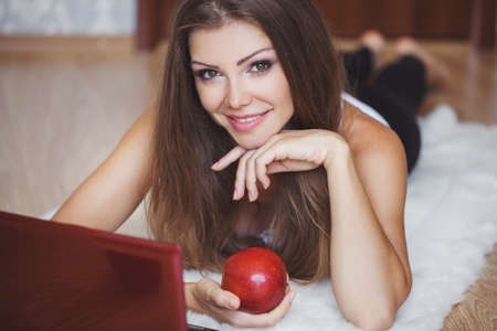 Portrait of a lovely young woman working on laptop while sitting on the floor