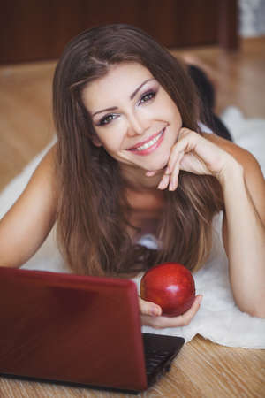 Portrait of a lovely young woman working on laptop while sitting on the floorの写真素材