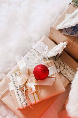 Christmas background with a red ornament, golden gift box, berries and fir in snowの写真素材