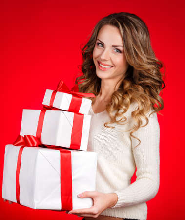 Woman wrapping Christmas presents  Christmas preparations concept with beautiful smile happy content young woman in her twenties with a red background の写真素材