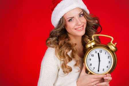 Pretty Woman In Santa Claus Costume Showing Clock Over Red の写真素材