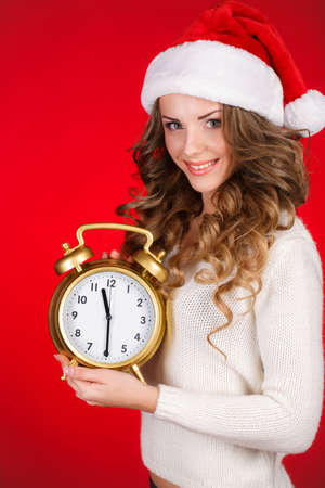 Pretty Woman In Santa Claus Costume Showing Clock Over Red の写真素材
