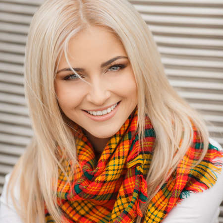 Close up portrait of young blonde beautiful woman in warm autumn scarf  Ourdoors 