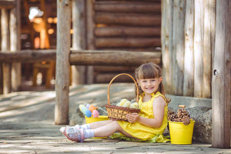 cute girl sitting in the village with her yellow chicken in the bucketの写真素材