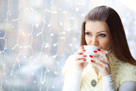 pretty young woman sitting in the cafe with a cup of coffeeの写真素材
