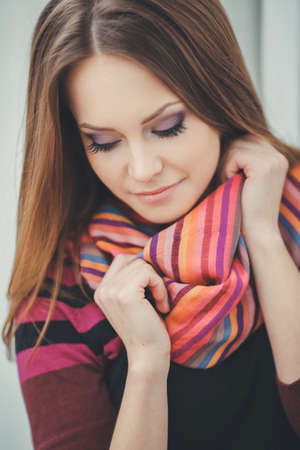 Portrait of beautiful young brunette woman in warm autumn scarf on the street の写真素材