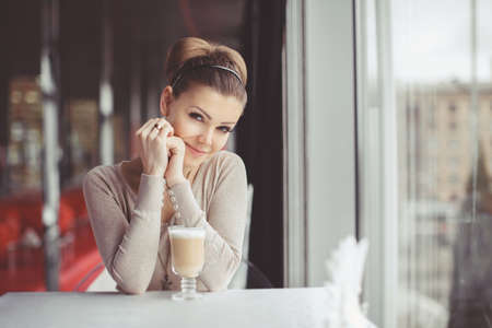 pretty young woman sitting in a cafe with a cup of coffee latteの写真素材