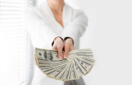 Portrait of a happy woman with a fan of american dollar currency notesの写真素材
