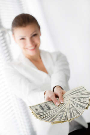 Portrait of a happy woman with a fan of american dollar currency notesの写真素材