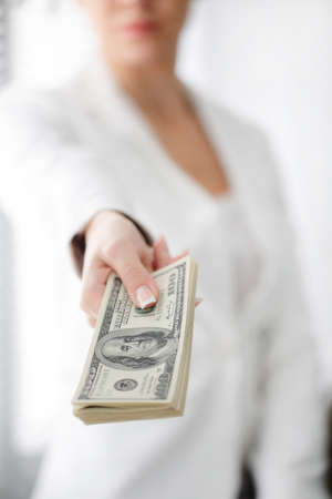 Portrait of a happy woman with a fan of american dollar currency notesの写真素材