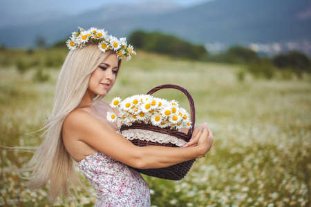 Attractive blonde in chamomile field  Young woman in wreath surrounded by chamomilesの写真素材