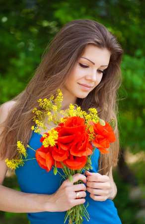 Portrait of cheerful woman outdoor with red poppy flowers in her handsの写真素材