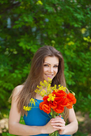 Portrait of cheerful woman outdoor with red poppy flowers in her handsの写真素材