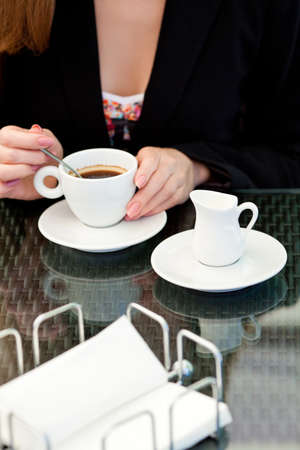 woman holding hot cup of coffee sitting in a cafeの写真素材