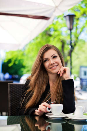 Portrait of young beautiful woman sitting in a cafe outdoor drinking coffeeの写真素材