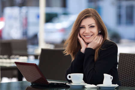 Portrait of young beautiful woman sitting in a cafe outdoor drinking coffeeの写真素材