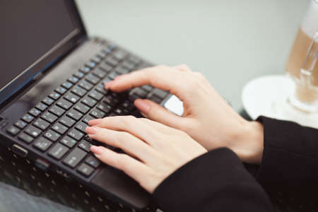 Portrait of beautiful woman in winning pose and smiling sitting in a cafe with laptop outdoorの写真素材