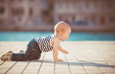 Portrait of happy little boy playing outdoors at dock near the sea