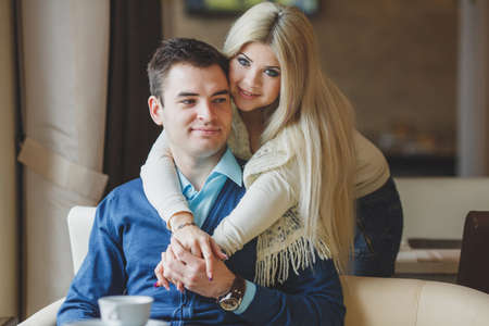 Portrait of happy young couple embracing each other and drinking coffee in a cafeの写真素材