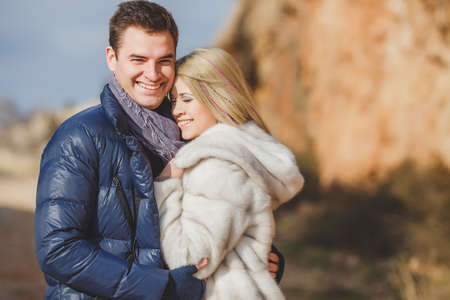 Portrait of young embracing couple  Man and woman in autumn scenery and mountains behind, outdoorの写真素材