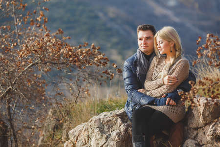 Portrait of young embracing couple  Man and woman in autumn scenery and mountains behind, outdoorの写真素材