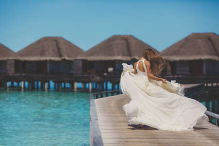 bride in wedding dress running and having fun on tropical island of maldivesの写真素材