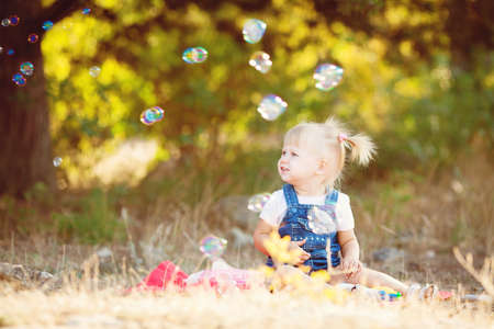 cute little girl eating a lollipop on the grass in summertimeの写真素材