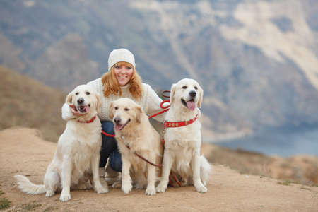Beautiful girl with her pet dog in the mountains on the background of the seaの写真素材