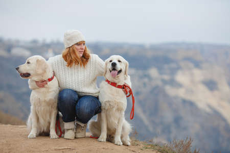 Beautiful girl with her pet dog in the mountains on the background of the seaの写真素材