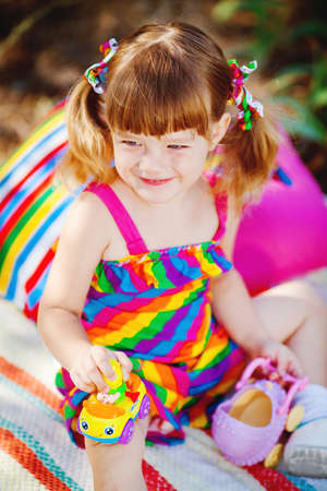 Little toddler girl sitting in green summer parkの写真素材
