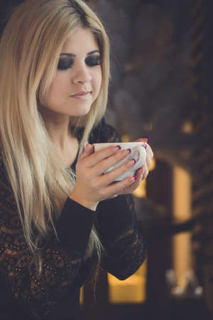 Portrait of young beautiful woman sitting in a cafe drinking coffeeの写真素材