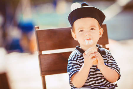 Adorable toddler boy eating delicious ice cream on a tropical beach