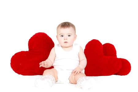 portrait of adorable Little infant girl hugging a large toy heart isolated on white backgroundの写真素材