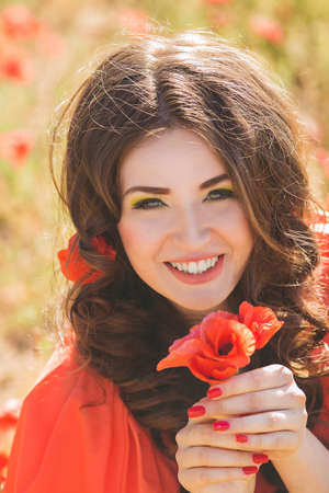 Lovely happy female closeup portrait, sitting in the poppy flower field, enjoying nature, summertime leisure conceptの写真素材