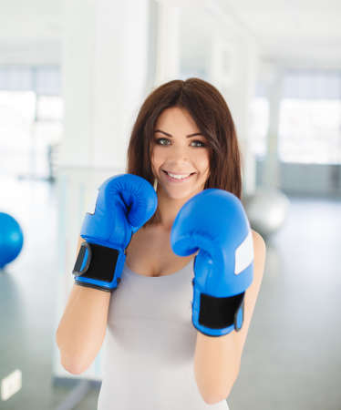 Boxer - fitness woman boxing wearing boxing gloves  Fitness boxing instructor punching fun and fresh towards camera  Beautiful mixed race Asian   Caucasian fitness girl in gymの写真素材