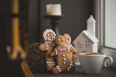 Smiling gingerbread man standing next to a Cup of coffee at the window, close with shallow DOF copy space for text in Internetの写真素材